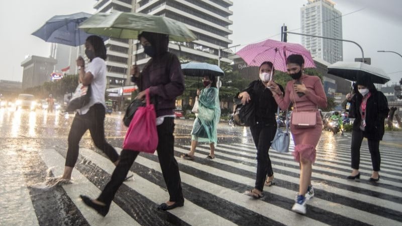 Warga berjalan saat hujan lebat di kawasan Sarinah Thamrin, Jakarta, Selasa (5/4/2022)