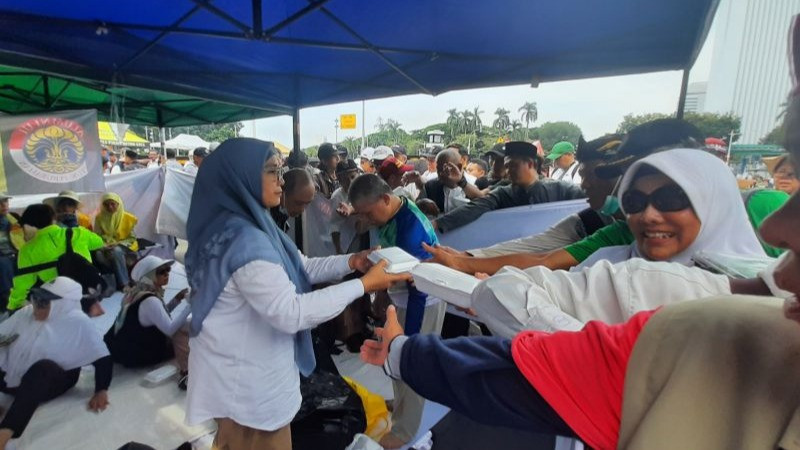 Kegiatan berbagi makanan di sela aksi unjuk rasa di dekat kawasan Monumen Nasional, Jalan Medan Merdeka Barat, Jakarta Pusat, Jumat (19/4/2024).