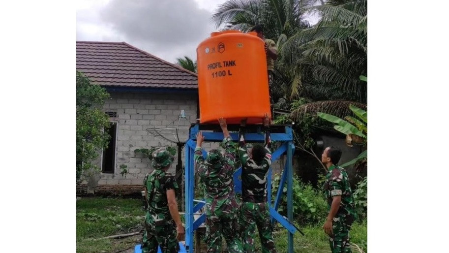 Prajurit TNI menaikan profil tank ke atas menara kayu untuk mampung air sumur bor