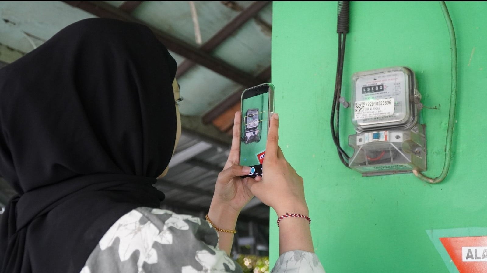 Ilustrasi pelanggan tengah memanfaatkan fitur SwaCAM di aplikasi PLN Mobile untuk mencatat stand meter listrik