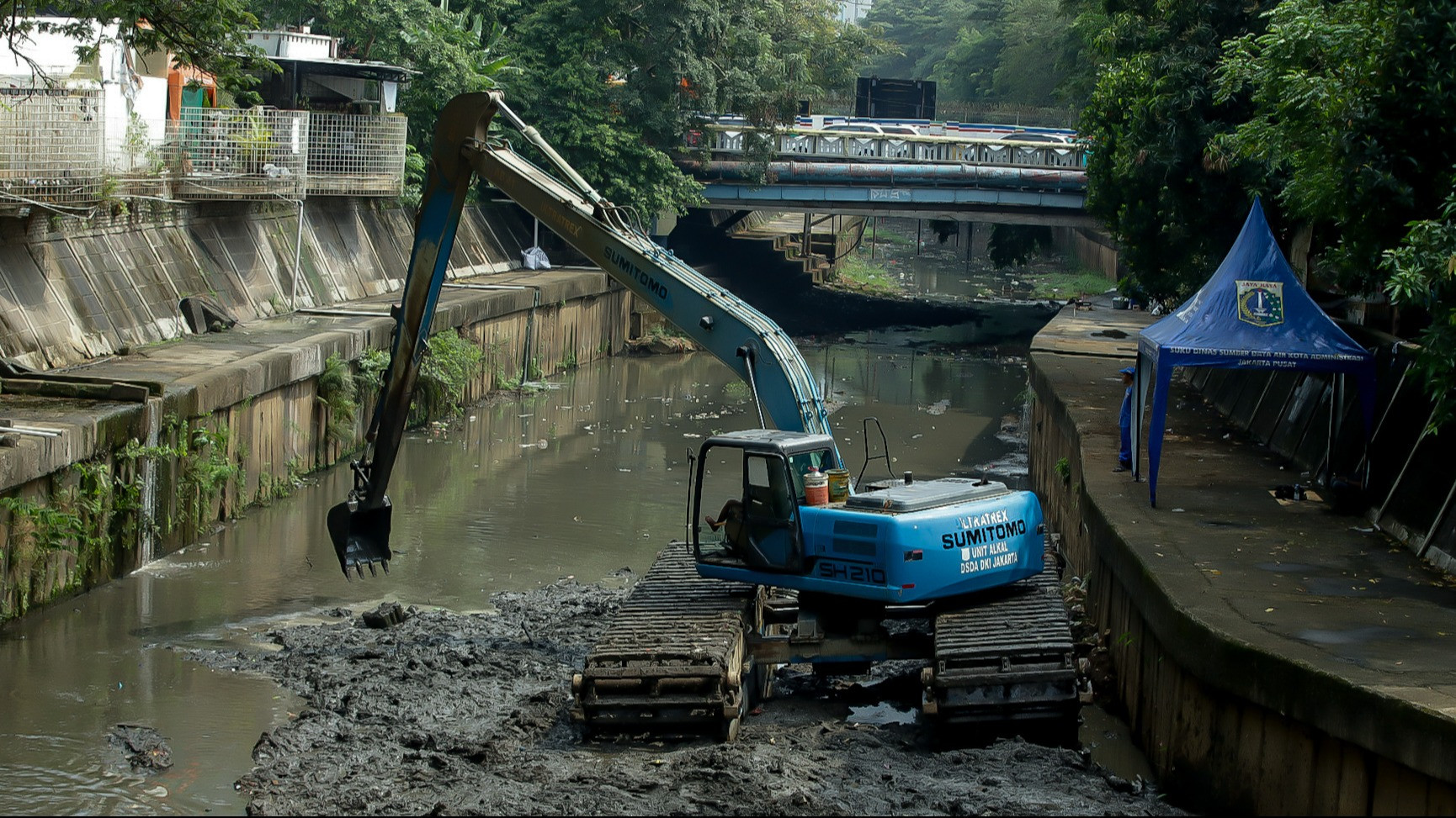 Petugas melakukan pengerukan lumpur di aliran Kali Ciliwung, kawasan Matraman, Jakarta Timur, menggunakan alat berat pada Jumat (22/5/2026).