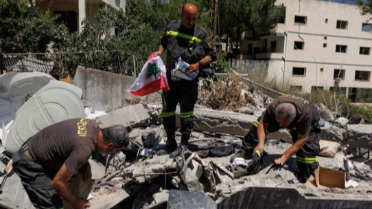 Polisi dan pemadam kebakaran memegang Bendera Lebanon di bangunan runtuh yang dihancurkan Israel di tengah kesepakatan perdamaian Amerika Serikat (AS)-Iran