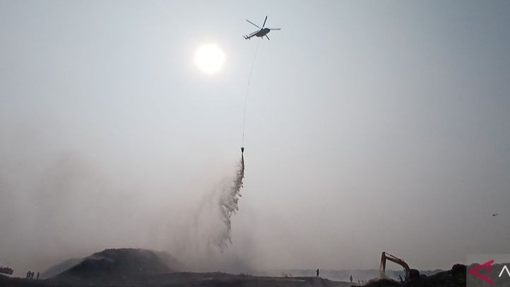Sejumlah petugas beserta alat berat dan helikopter water bombing beraktivitas dalam operasi pemadaman kebakaran di area kTPA Jatiwaringin, Mauk, Kabupaten Tangerang, Banten, pada Senin (6/8/2026).