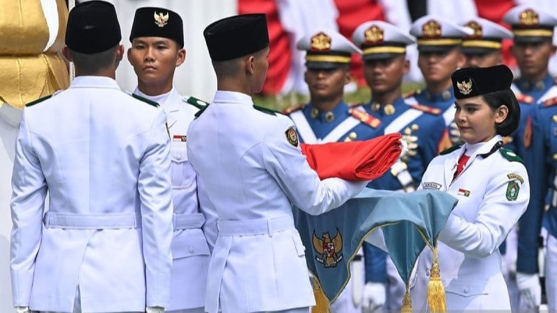 Anggota Paskibraka Celina Olivia Apriani Theo (kanan) menyerahkan bendera Merah Putih kepada rekannya pada Upacara Kemerdekaan Ke-81 Republik Indonesia di Istana Merdeka, Jakarta, Senin (17/8).