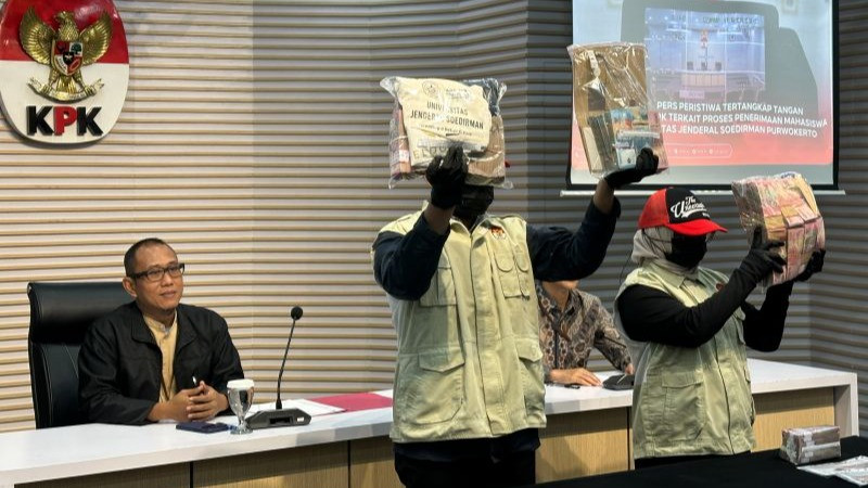 Pelaksana Tugas (Plt.) Direktur Penyidikan KPK Achmad Taufik Husein (kiri) menunjukkan barang bukti kasus dugaan korupsi Unsoed, di Gedung Merah Putih KPK, Jakarta, Jumat (21/8/2026).