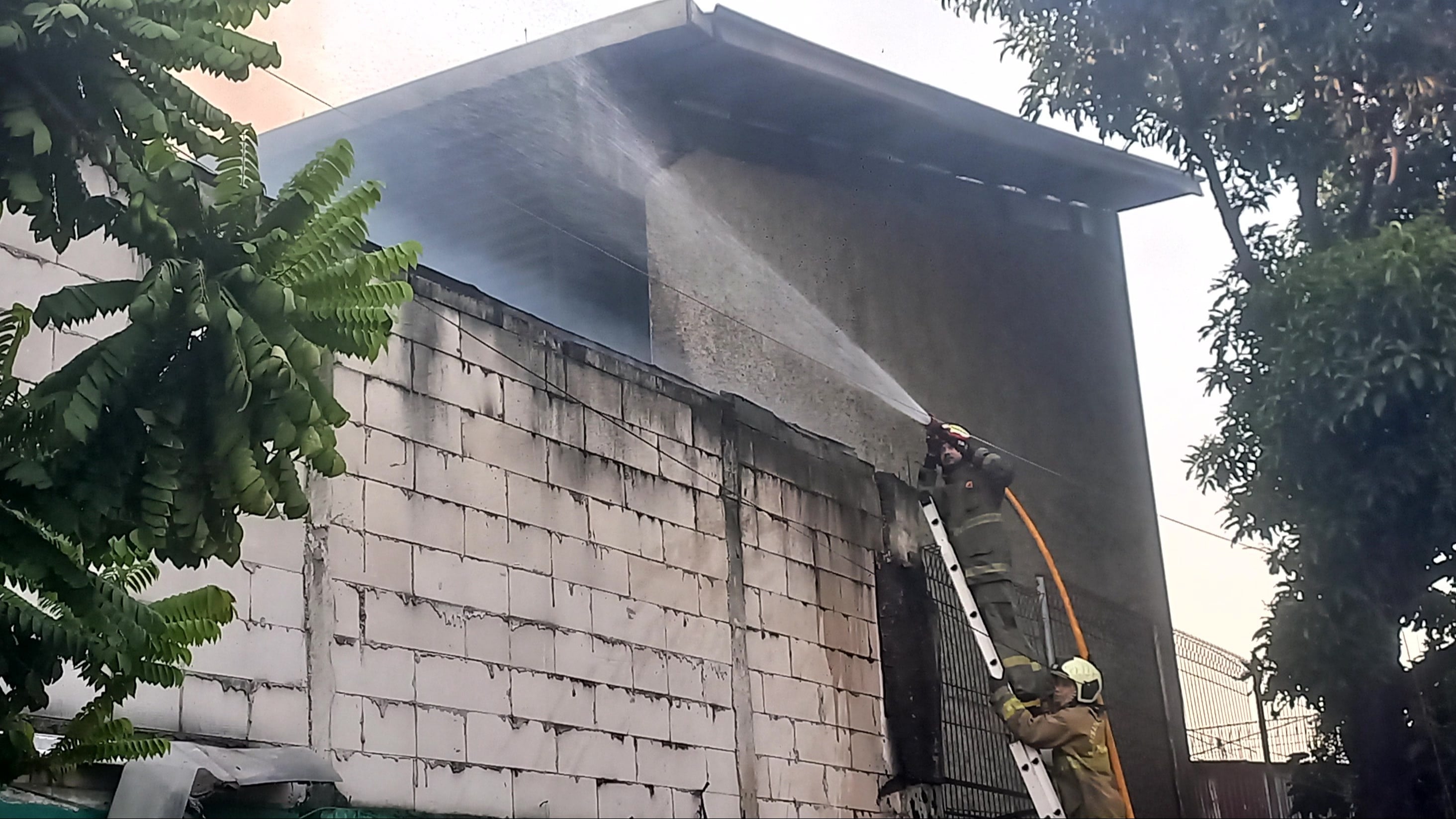 Pemadam kebakaran sedang berusaha memadamkan api di gudang properti stasiun televisi di Kebon Jeruk, Jakarta Barat, Minggu (6/9/2026).