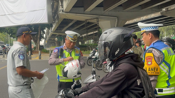 Kasat Lantas Polres Metro Jakarta Selatan, Kompol Mujiyanto dan petugas Jasa Raharja saat membagikan helm di Jalan Fatmawati, Jakarta Selatan, Selasa (27/10/2026).